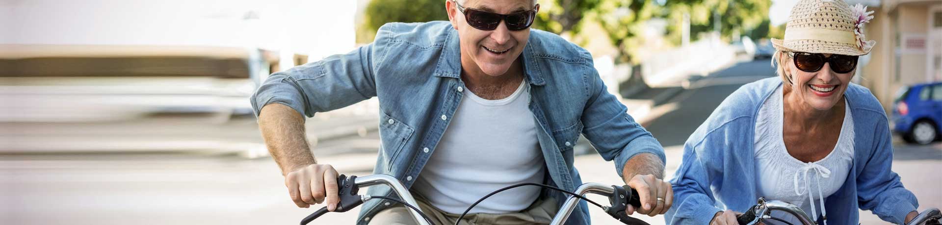 Happy mature couple going for a bike ride in the city